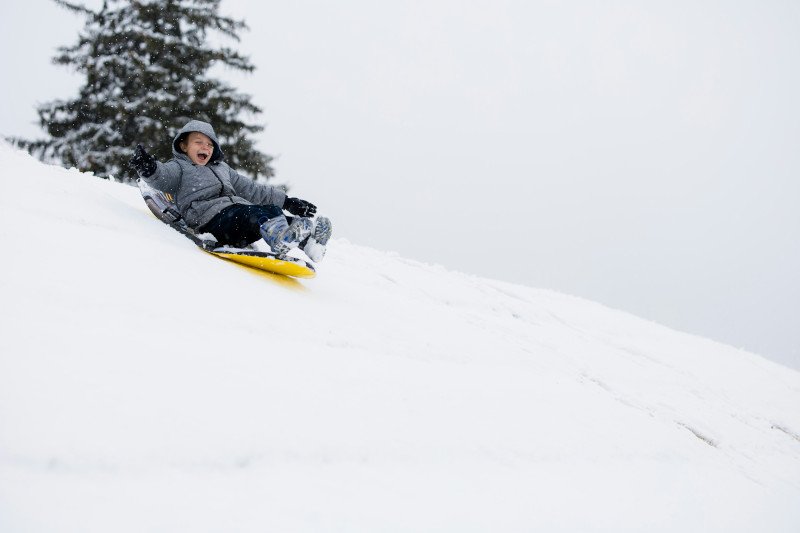 Kid sledding down a hill with a big smile!